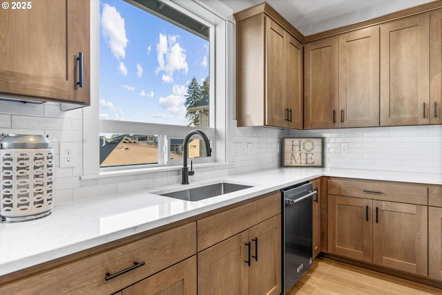 kitchen featuring sink, light wood-type flooring, light stone counters, and decorative backsplash