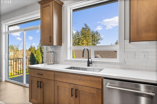 kitchen with sink, tasteful backsplash, dishwasher, and light hardwood / wood-style flooring