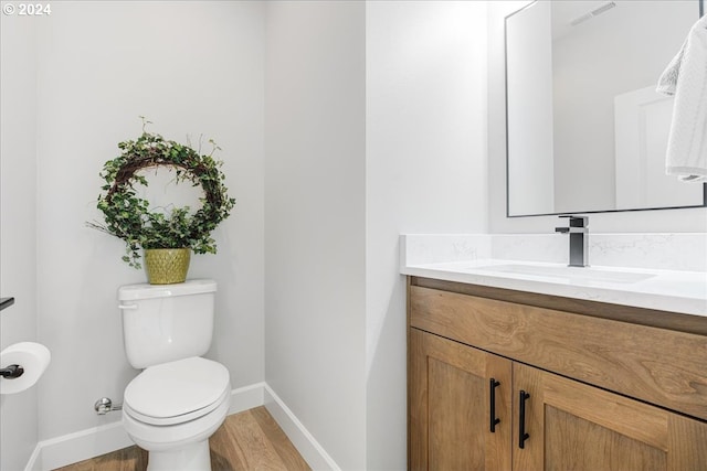 bathroom featuring toilet, hardwood / wood-style flooring, and vanity