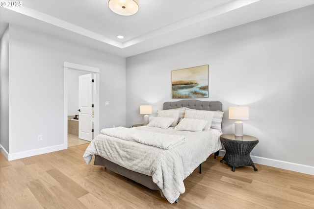 bedroom featuring ensuite bath and light hardwood / wood-style floors