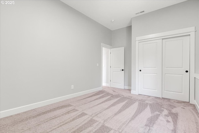 unfurnished bedroom featuring light colored carpet and a closet