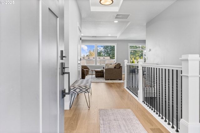 corridor featuring light hardwood / wood-style floors and a tray ceiling