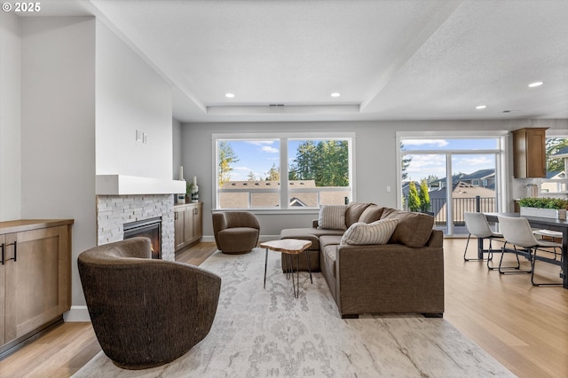 living room with a fireplace, a textured ceiling, and light hardwood / wood-style flooring