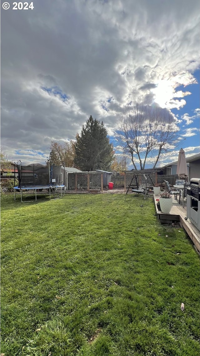 view of yard featuring a trampoline and a deck