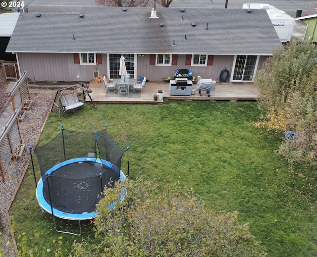 rear view of property with outdoor lounge area, a lawn, and a trampoline