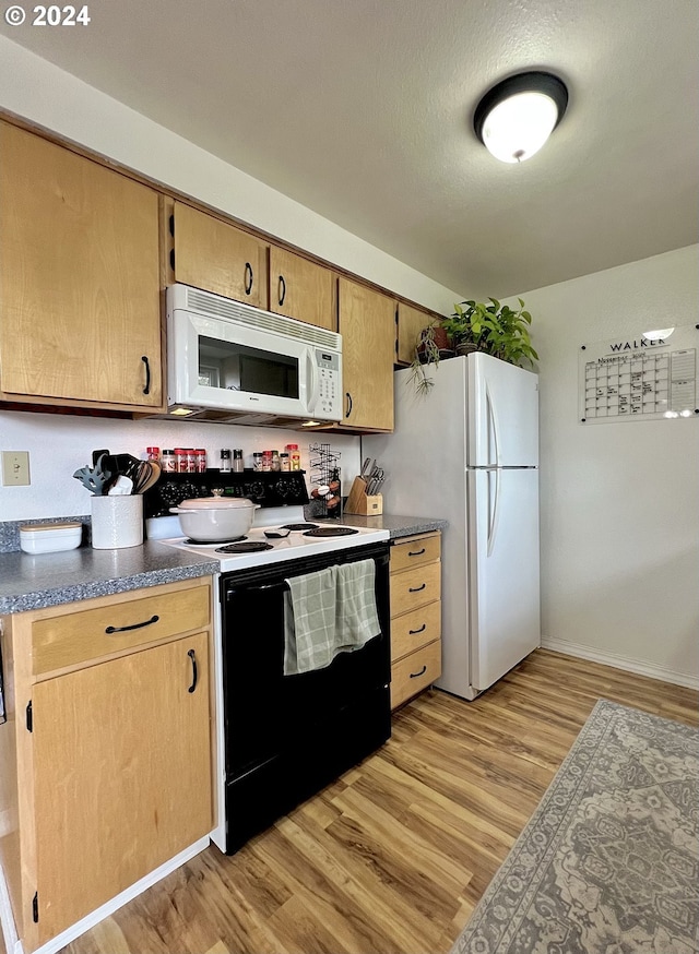 kitchen with light wood-type flooring, a textured ceiling, and white appliances