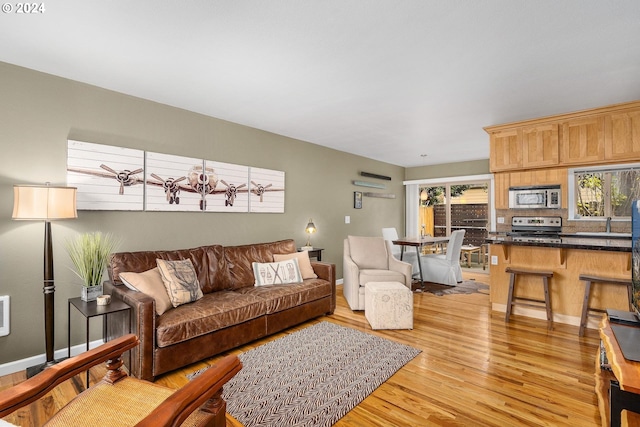 living room featuring sink, light wood-type flooring, and a wealth of natural light