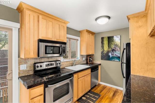 kitchen with light brown cabinetry, sink, tasteful backsplash, light wood-type flooring, and stainless steel appliances