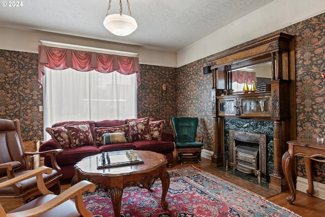 living room featuring ornamental molding, a high end fireplace, wood-type flooring, and a textured ceiling