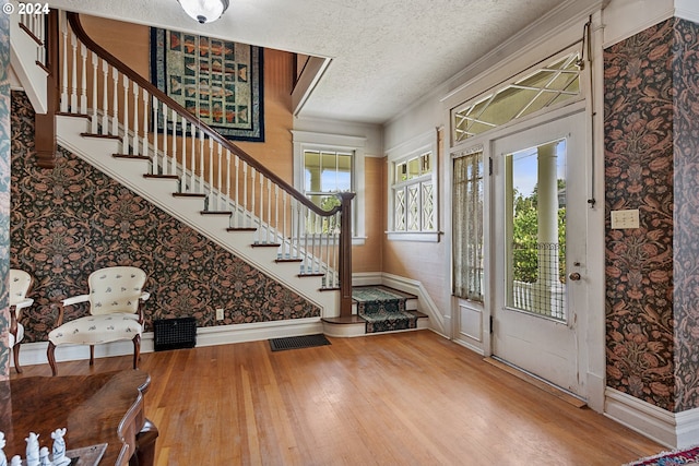 foyer featuring hardwood / wood-style floors, ornamental molding, and a textured ceiling