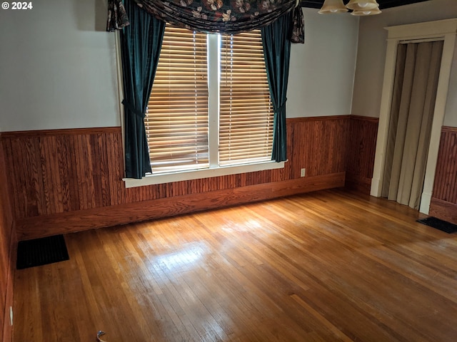 empty room with wood-type flooring, a healthy amount of sunlight, and wooden walls