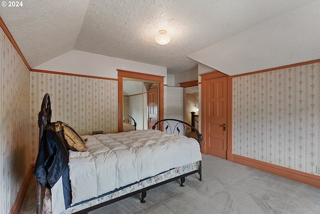 bedroom with light carpet, vaulted ceiling, a textured ceiling, and a closet