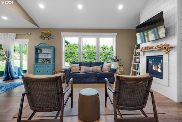 living room featuring plenty of natural light, lofted ceiling, and light wood-type flooring