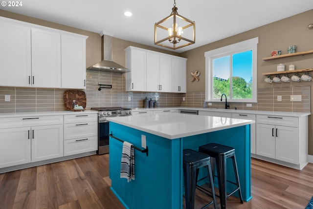 kitchen with a center island, white cabinets, wall chimney exhaust hood, stainless steel range, and dark hardwood / wood-style flooring