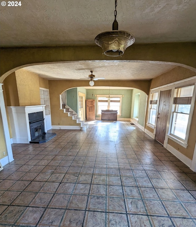 unfurnished living room with a textured ceiling, plenty of natural light, and ceiling fan