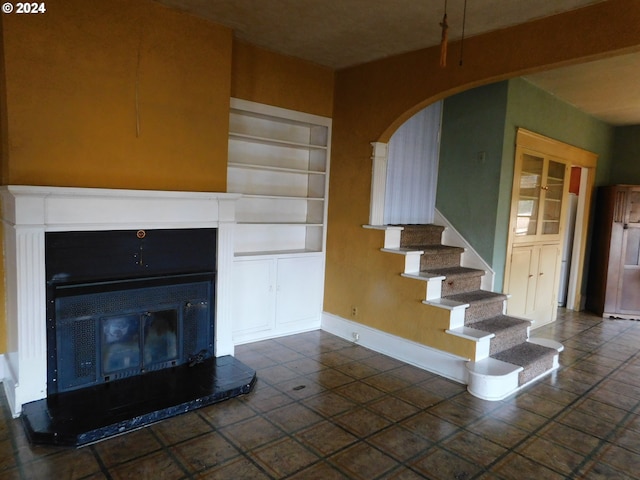 unfurnished living room featuring built in features and dark tile patterned floors