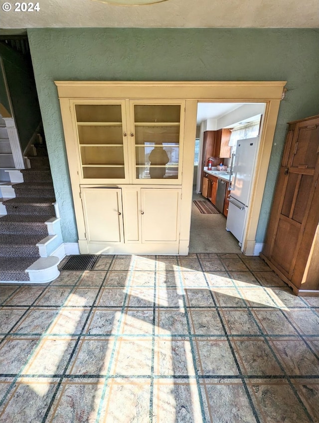 interior space with cream cabinets, white refrigerator, and stainless steel dishwasher