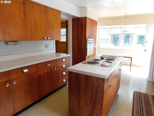 kitchen with pendant lighting, white appliances, a kitchen island, and plenty of natural light