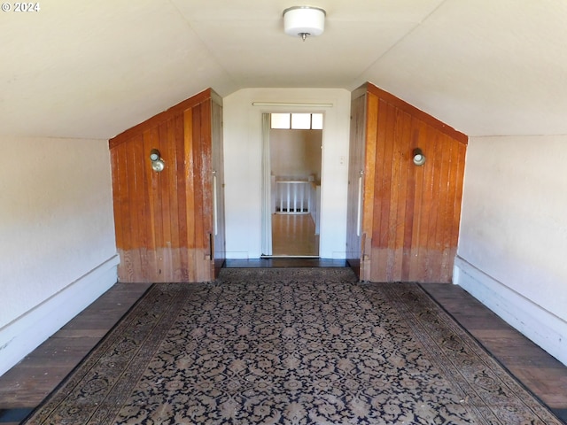 additional living space with dark hardwood / wood-style flooring, vaulted ceiling, and wood walls