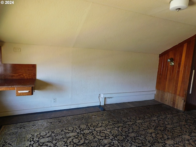 spare room featuring lofted ceiling and wooden walls