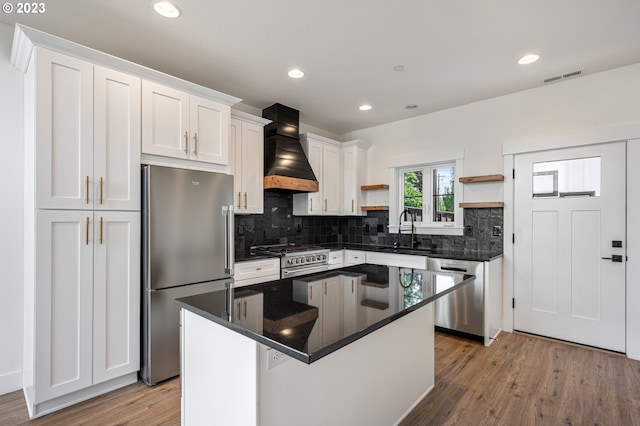 kitchen with high end appliances, light hardwood / wood-style flooring, a kitchen island, premium range hood, and white cabinets