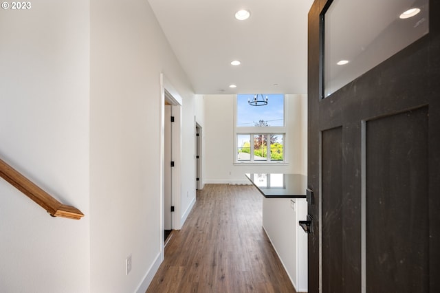 hallway with dark wood-type flooring and a chandelier