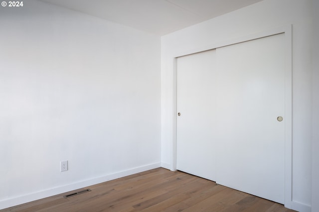 unfurnished bedroom with hardwood / wood-style flooring and a closet