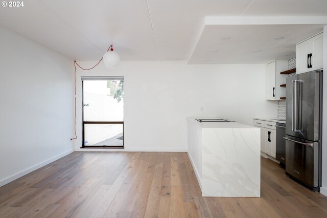 kitchen with tasteful backsplash, stainless steel appliances, white cabinetry, and light hardwood / wood-style flooring