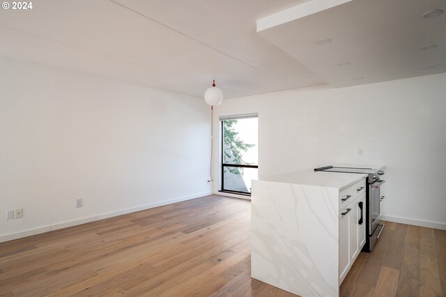 kitchen featuring white cabinets, light stone counters, electric range, and light hardwood / wood-style floors