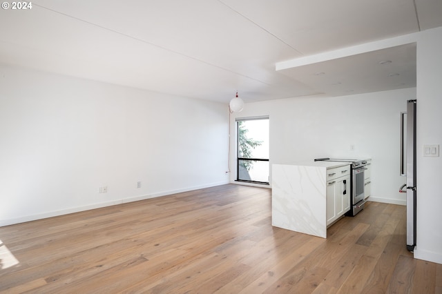 kitchen with hanging light fixtures, appliances with stainless steel finishes, white cabinets, and light hardwood / wood-style floors