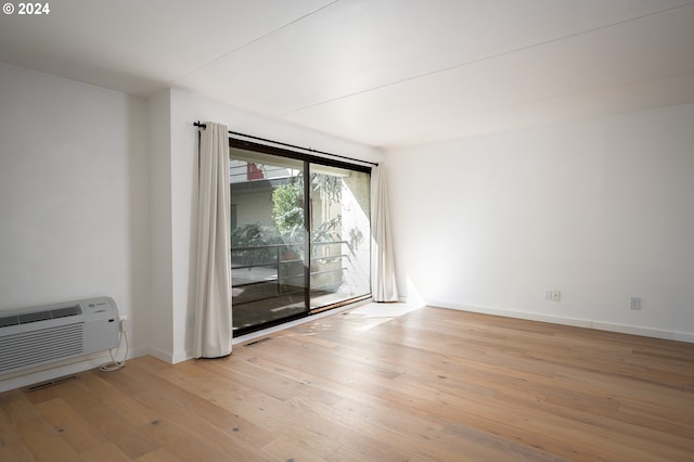 spare room featuring a wall mounted air conditioner and light hardwood / wood-style flooring