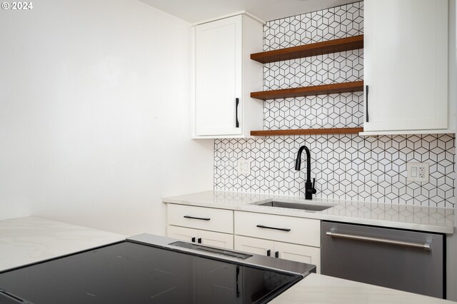 kitchen with stainless steel dishwasher, white cabinetry, backsplash, and sink