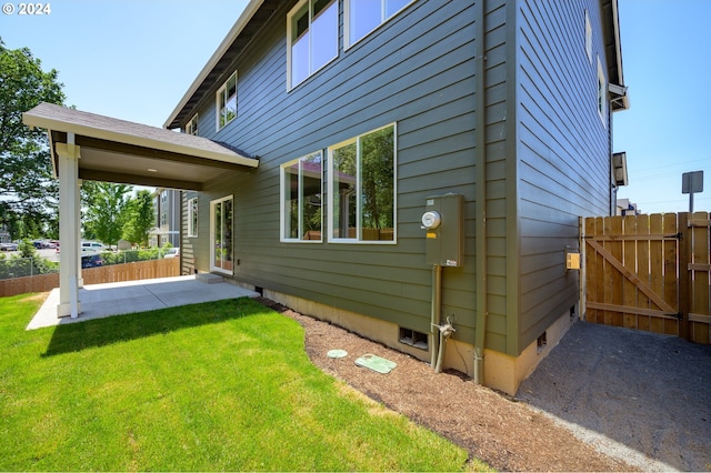 view of side of home featuring a patio area and a lawn