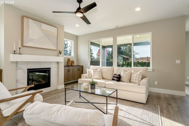 living room with a tile fireplace, light hardwood / wood-style flooring, and ceiling fan