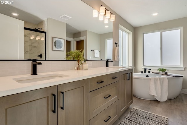 bathroom with vanity, wood-type flooring, independent shower and bath, and tasteful backsplash