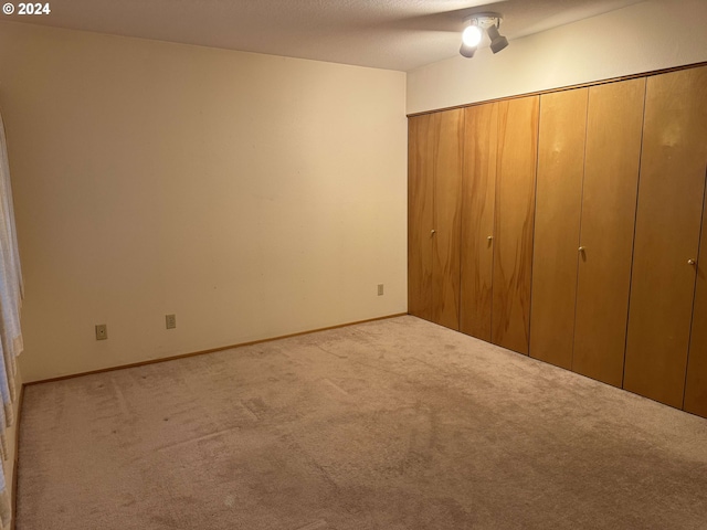 unfurnished bedroom featuring ceiling fan, light colored carpet, and a closet