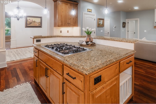 kitchen featuring a kitchen island, stainless steel gas cooktop, hanging light fixtures, a chandelier, and dark hardwood / wood-style floors