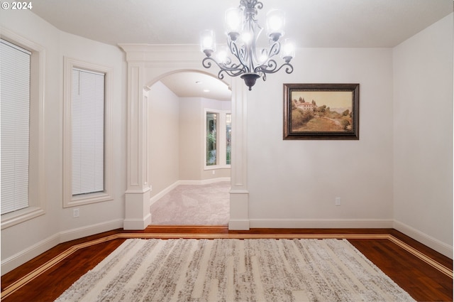 unfurnished dining area featuring a notable chandelier and dark hardwood / wood-style floors