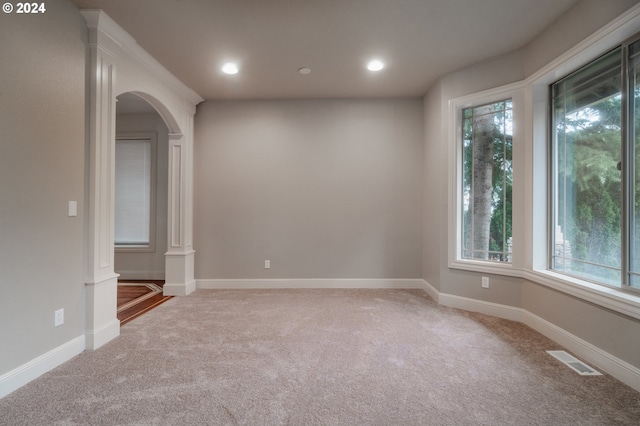 carpeted empty room featuring ornate columns