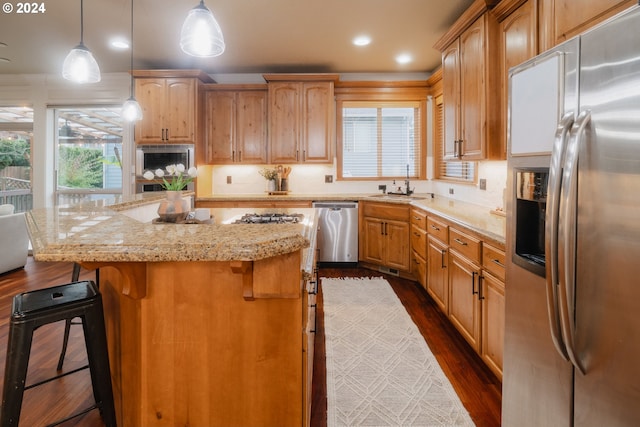 kitchen featuring a kitchen island, a breakfast bar, stainless steel appliances, dark wood-type flooring, and decorative light fixtures