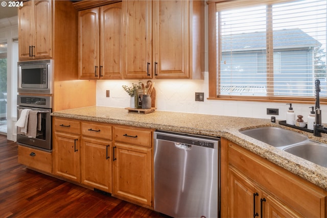 kitchen with sink, dark wood-type flooring, light stone counters, and stainless steel appliances