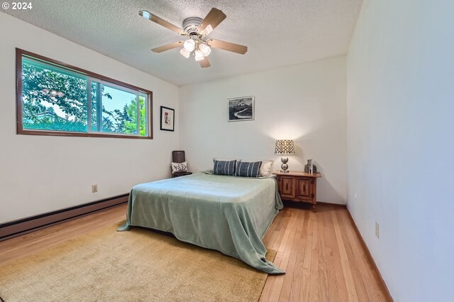 bedroom with ceiling fan, a textured ceiling, and light hardwood / wood-style floors