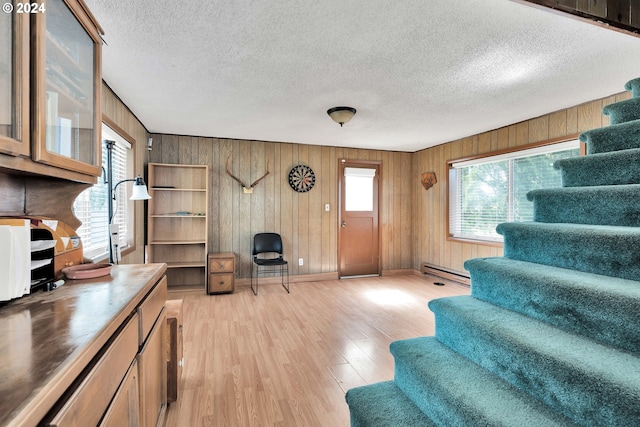 living room with light wood-type flooring, a baseboard radiator, stairway, and a textured ceiling