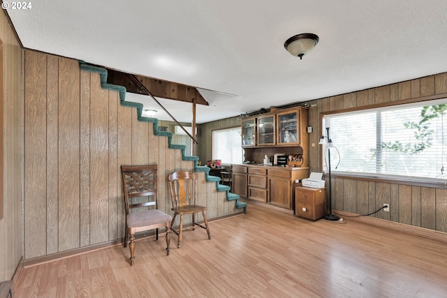 sitting room with stairs, light wood finished floors, wood walls, and baseboards