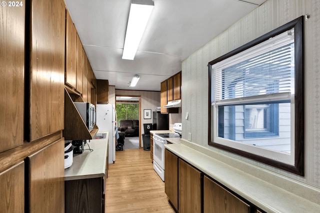 kitchen with light wood-style flooring, under cabinet range hood, white appliances, light countertops, and brown cabinets