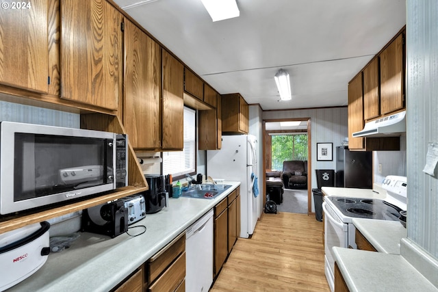 kitchen featuring light countertops, white appliances, brown cabinets, and under cabinet range hood