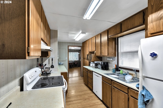 kitchen featuring light countertops, white appliances, light wood-type flooring, and a sink