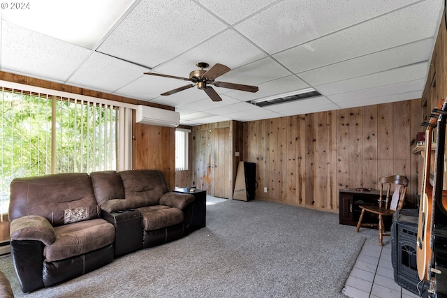 living area featuring ceiling fan, wood walls, a wall mounted AC, and a wood stove