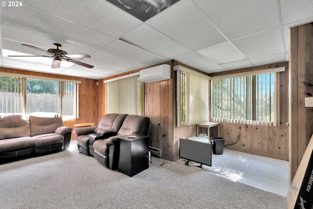 living area featuring ceiling fan, a wall unit AC, a paneled ceiling, and wooden walls