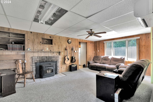 living room with light carpet, a paneled ceiling, a ceiling fan, and wooden walls